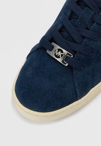 Ναυτικό μπλε σουέντ αθλητικό παπούτ�σι με υφή, με σκούρα κορδόνια και μεταλλική ασημένια διακοσμητική λεπτομέρεια με λογότυπο στη γλώσσα. Σόλα σε κρεμ απόχρωση.