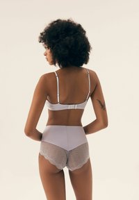 Light gray bra with adjustable straps and hook closure, paired with high-waisted shorts featuring a textured herringbone pattern and scalloped edges.