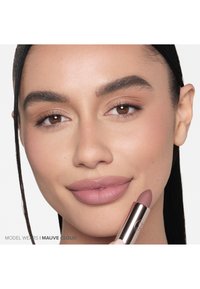 Lipstick in een rozen mauve tint, vastgehouden door een model. De lippenstift heeft een gladde textuur en een metallic roségouden verpakking. De huidtint is natuurlijk en stralend.