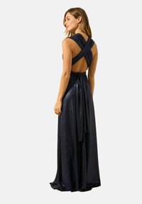 Robe de soirée sans manches bleu marine avec un design dos nu et des bretelles croisées. Présente une jupe fluide et un détail de taille nouée.