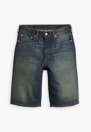 Sötétkék farmer nadrág, kopott részekkel, öt zsebbel, fém gombos záródással és narancssárga varrási akcentusokkal, egyenes szabású.