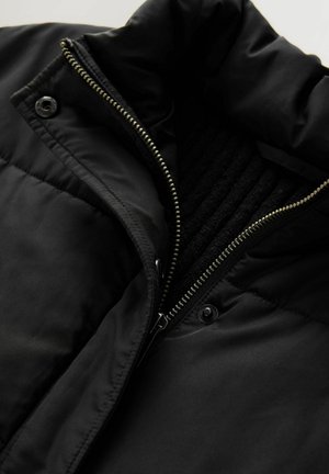 Čierna bunda s vysokým golierom, vybavená predným zipsom, zapínaním na cvoky a textúrovanou vnútornou podšívkou. Hladká, vodeodolná tkanina.