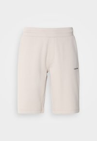 Shorts de sport beige clair en mélange de coton, dotés d'une taille élastique, de poches latérales et d'un petit logo noir sur une jambe.