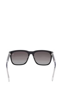 Svarta solglasögon med fyrkantig ram, gråtonade linser och transparenta skalmar som är vinklade utåt, på en vit bakgrund.