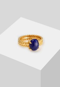 Guldtonet ring med en central oval blå sten, med en tekstureret ring af små perler og glatte kanter, lavet af sterlingsølv.