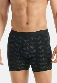 Svarta boxer briefs med ett geometriskt mönster i mörkgrön och grå, gjorda av ett mjukt, elastiskt tyg, med en elastisk midja.