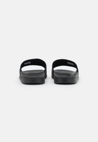 Svarta slidesandaler med en platt, strukturerad gummisula och öppen baksida. Ovandelen har två breda remmar för komfort och stöd.