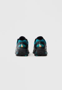 Pari di scarpe sportive nere e teal viste da dietro su uno sfondo bianco, con loghi Air Max visibili sui talloni.