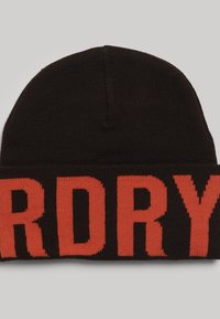 Zwarte gebreide beanie met opvallende rode letters "DRY" over de boord. Zachte textuur met een ronde top.