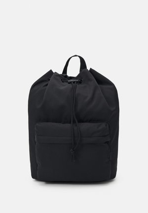 Black drawstring backpack made of durable fabric, featuring a front zipper pocket and a top handle for easy carrying. Smooth texture.