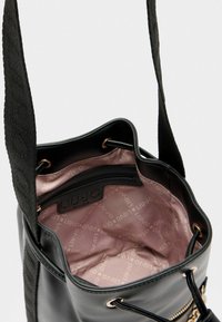 Zwarte emmer tas met een gestructureerde stofriem, gouden hardware en een lichtrozevoering met een ritsvak en logo patroon.