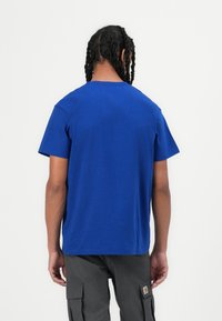 Blue cotton t-shirt with a rounded neckline, short sleeves, and a relaxed fit. Visible texture with a smooth finish, no patterns or accents.