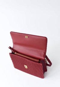 Borsa a tracolla in pelle rossa con texture trapuntata, hardware dorato e scomparto con zip. Interno in tessuto liscio.