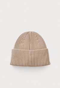 Bonnet en tricot beige avec une texture côtelée et un revers replié. Présente des lignes verticales et un sommet légèrement effilé. Tissu doux, design chaud.