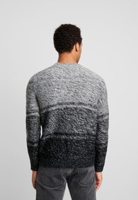 Pull en maille avec un dégradé de nuances de gris, tissu texturé, col rond et manches longues. Ourlet et poignets côtelés visibles.