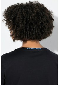 Musta t-paita pyöreällä pääntiellä ja lyhyillä hihoilla. Takana sininen tekstitulostus, jossa lukee "YOU ARE UNIQUE." Pinta on sileä.