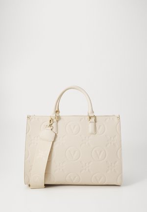 Sac à main beige avec motifs circulaires en V embossés et motifs floraux, équipé de deux anses et d'une large bandoulière amovible.