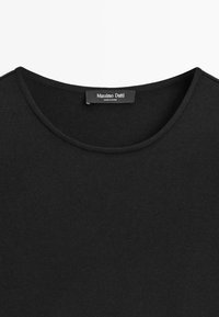 Czarny prążkowany top z dekoltem w kształcie zaokrąglonej lini i przeszyciem przy szyi, z metką Massimo Dutti z napisem "Made in China".