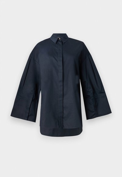 Navy blue oversized shirt made of smooth cotton fabric. Features a classic collar, front button closure, and exaggerated sleeves.