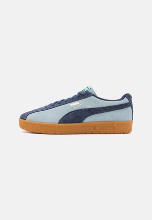 Puma sneakers with a light blue suede upper, navy accents, and a tan rubber sole. Features laces and a small logo on the side.