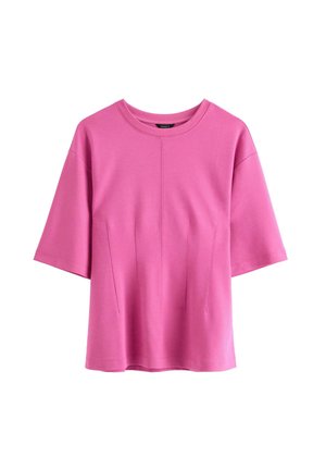 Růžový top s krátkým rukávem vyrobený z hladkého materiálu, s kulatým výstřihem a dvěma vertikálními švy na přední straně pro zvýšení designového zájmu.