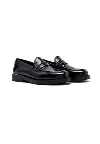 Un par de mocasines de cuero negro brillante con tacones bajos y costuras decorativas, presentados sobre un fondo blanco.