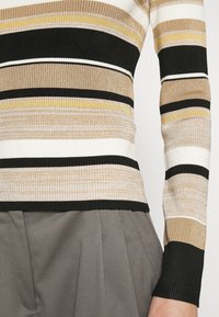 Rippstrick Longsleeve-Oberteil in Beige-, Schwarz-, Weiß- und Gelbstreifen; figurbetonter Schnitt mit kontrastierenden schwarzen Bündchen.