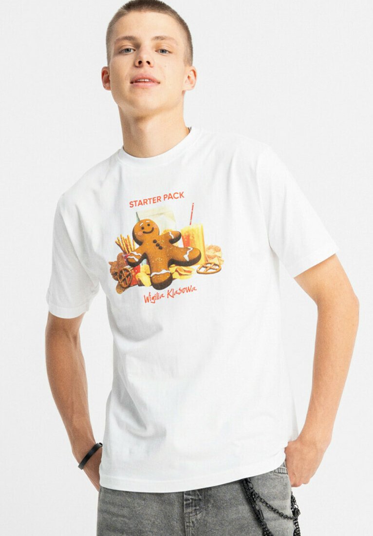 Biały bawełniany t-shirt z nadrukiem przedstawiającym piernikowego ludzika, przekąski oraz czerwony napis "STARTER PACK", z okrągłym dekoltem.