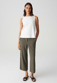 Top senza maniche a coste bianche, pantaloni larghi texturizzati verde oliva e sandali neri con fascia. Design semplice e moderno con tessuto morbido.