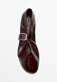 Vinrød lædersko med åben tå og spænde, med glat tekstur og rund form. Brandlogo synligt indeni.