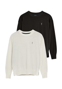 Två tröjor utställda tillsammans: en krämfärgad och en svart. Båda har rundad halsringning, långa ärmar och en liten broderad logotyp på bröstet.