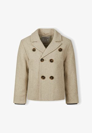 Bežo vilnos puspaltis su dvigubu užsegimu, dideliais rudo spalvos mygtukais, su įpjovomis apykaklėmis ir juodu pamušalu rankogaliuose.