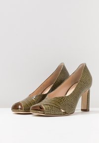 Escarpins ouverts verts à talon aiguille avec un motif serpent texturé, présentant une finition lisse à l'avant.