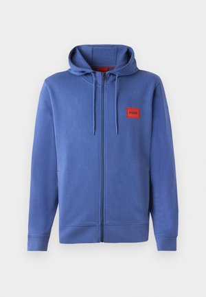 Blue zip-up hoodie with a hood, made from a soft material. Features red logo patch on the chest and ribbed cuffs and hem.
