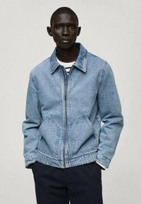 Jeans jakna svijetloplave boje s patentnim zatvaračem, ulomkom i dvostrukim velikim prednjim džepovima. Ima opušteni kroj i mekanu teksturu.