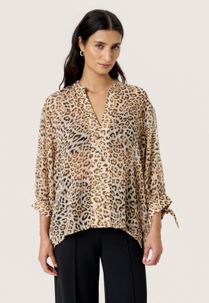 Bluse med leopardprint i gennemsigtigt stof, med V-hals, oprullede ærmer og løs pasform, kombineret med skræddersyede sorte bukser.