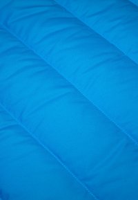 Tessuto trapuntato di un blu brillante con una texture liscia. Presenta cuciture diagonali che creano sezioni imbottite in tutto il tessuto.