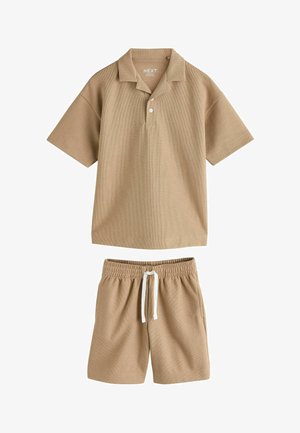 Bézs rövid ujjú galléros póló két gombbal, hozzá illő rugalmas derékpántos rövidnadrággal, fehér húzózsinórral.