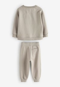Sweatshirt gris clair et pantalon de jogging assorti. Tissu doux et texturé avec des poignets côtelés, un col rond et des détails de couture subtils.