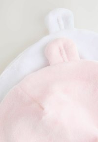 Tessuto morbido rosa e bianco con forme di orecchie arrotondate su uno sfondo neutro, che suggerisce accessori o giocattoli a tema animale carini.