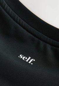 Top sport negru cu o textură netedă, având un decolteu rotund și cuvântul „self.” imprimat alb pe partea din față.
