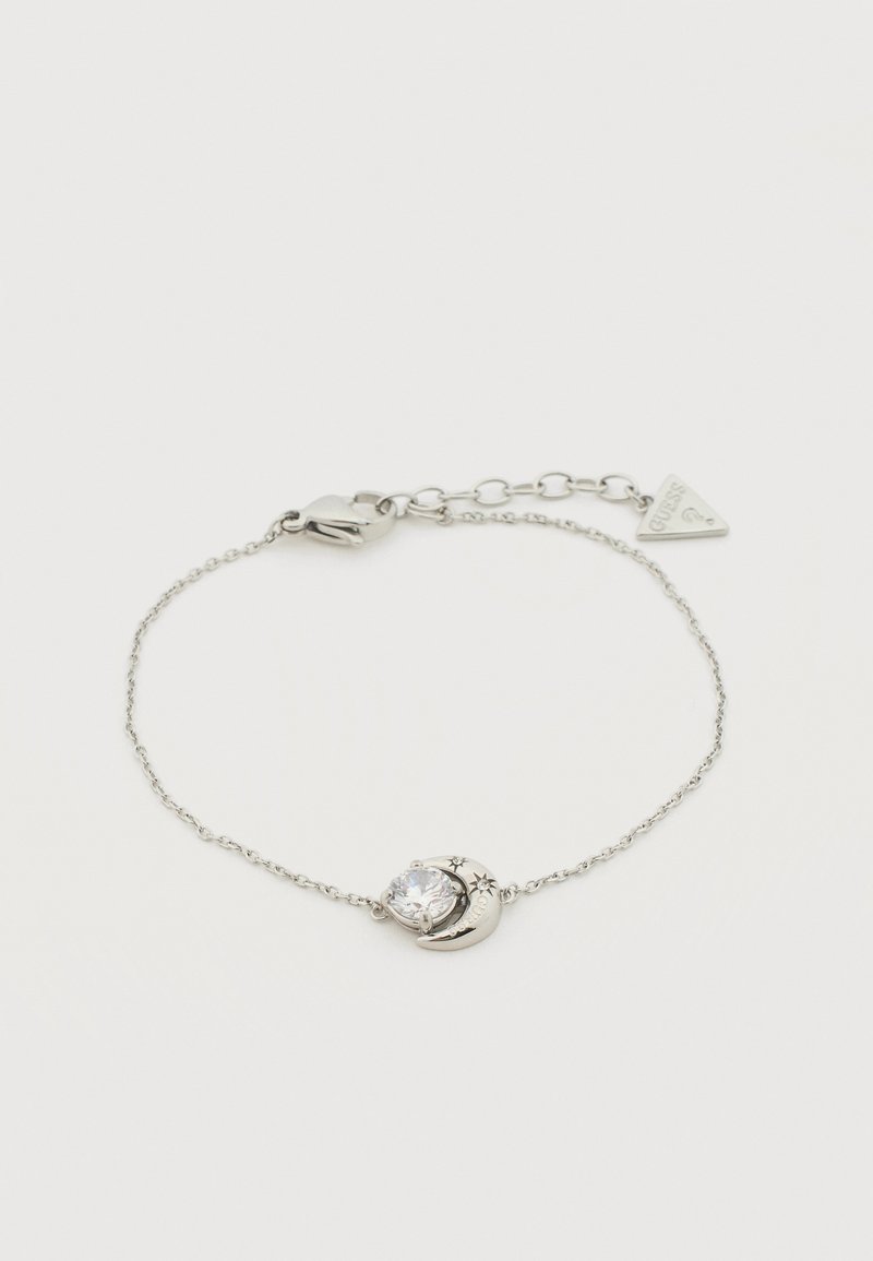 Bracelet délicat en chaîne d'argent avec un pendentif en forme de croissant de lune et d'étoile tenant une pierre précieuse claire, doté d'un fermoir ajustable et d'une étiquette de marque.