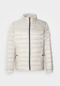 Veste matelassée beige clair avec col montant, fermeture éclair noire sur le devant, deux poches latérales à boutons-pression et poignets élastiques.