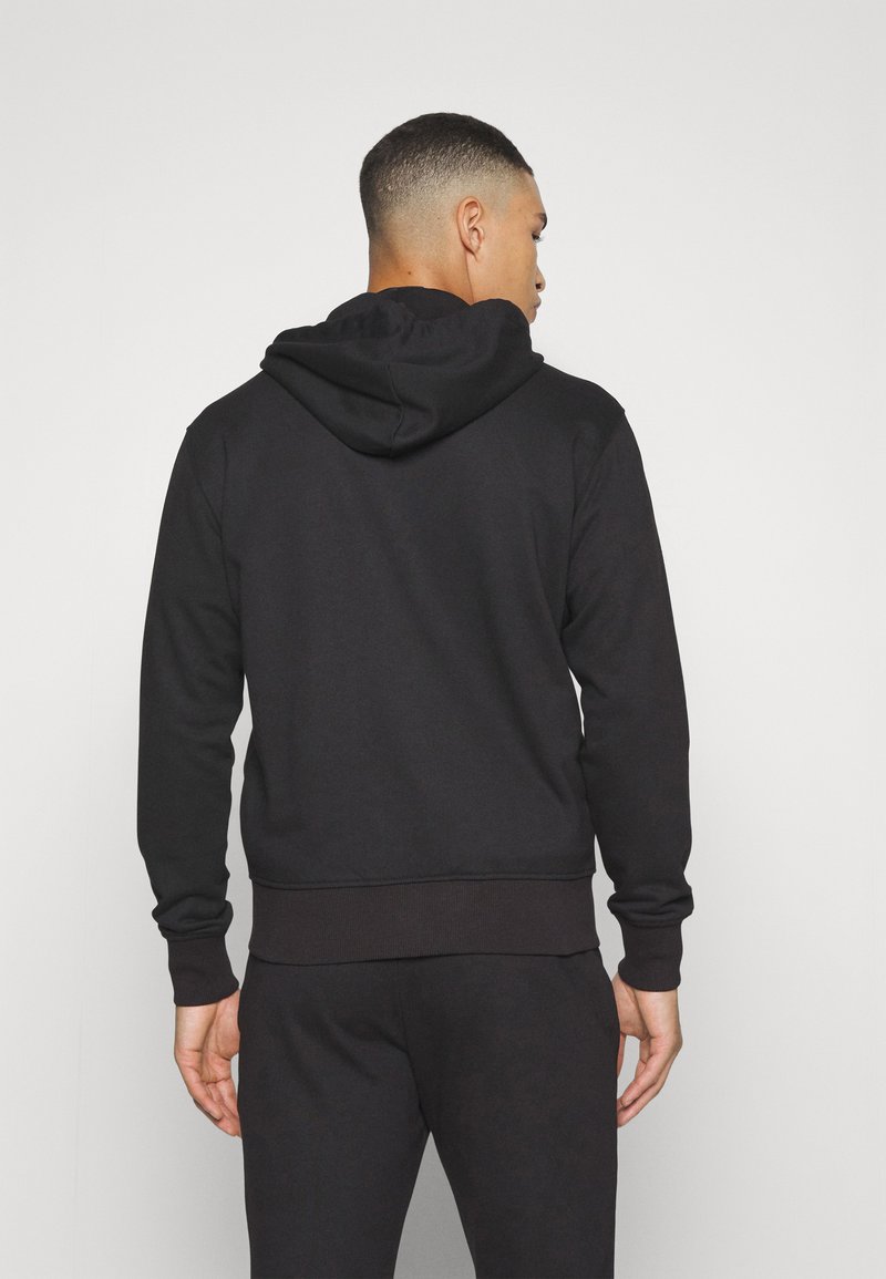 Zwarte hoodie gemaakt van zacht materiaal. Beschikt over lange mouwen, een kangoeroezak en een geribde tailleband voor een getailleerde uitstraling.