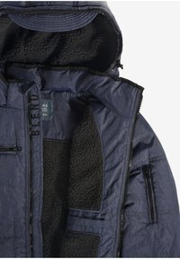 Marineblauwe jas met een getextureerde, met fleece gevoerde binnenkant, ritssluitingen aan de zakken en een gladde buitenstof. Voorzien van een capuchon en een ritssluiting aan de voorkant.