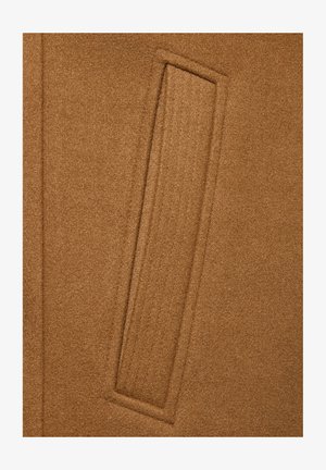 Zbliżenie brązowego wełnianego płaszcza z kieszenią z prostokątnym przeszyciem i otwarciem na krawędzi.