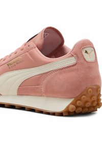 Puma Easy Rider sportcipők rózsaszín suede anyagban, krém színű részletekkel, texturált gumitalppal és arany színű logóval az oldalukon.