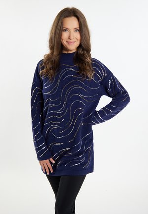 Granatowy sweter o luźnym kroju, z teksturowanymi, falistymi wzorami w kolorze srebrnym i złotym. Miękki, dziany materiał z długimi rękawami.
