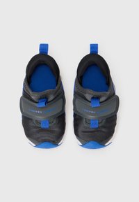 Baskets noires et bleues avec un dessus texturé, un bout renforcé et une sangle réglable portant la marque "23SEVEN JORDAN" ; design léger.