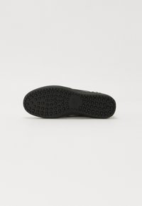 Fekete sneaker talp, textúrált gumis felülettel, szögletes és négyzet alakú mintázattal a tapadás és tartósság érdekében.